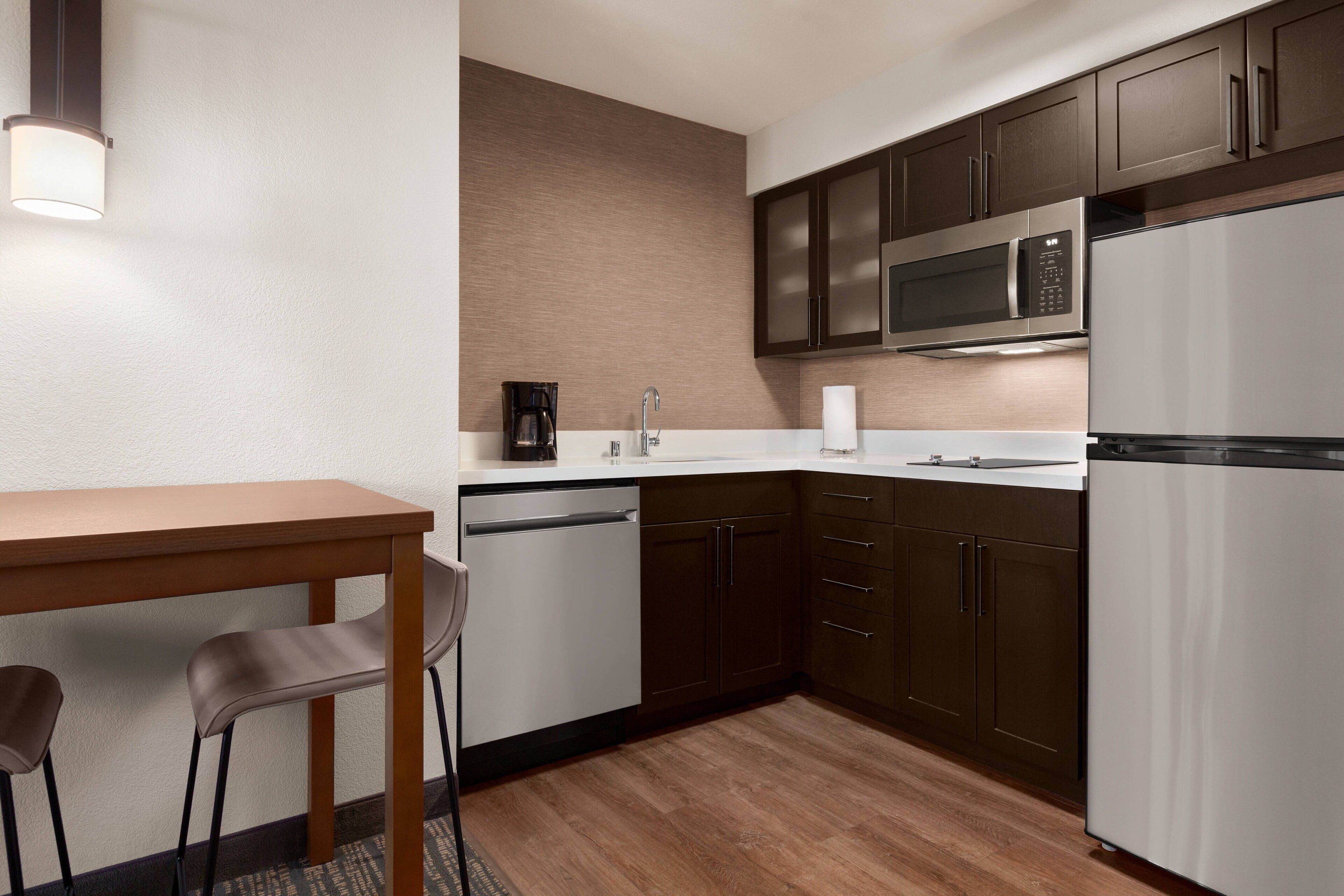 Cocina compacta con microondas, refrigerador y cafetera sobre la encimera.
