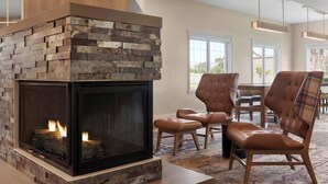 A modern living room with a stone fireplace, leather chairs, and a dining area. - Residence Inn by Marriott Salinas Monterey (Salinas)