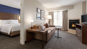 A hotel room with a bed, a sofa, a small table, a TV, and a fireplace. - Residence Inn by Marriott Salinas Monterey (Salinas)