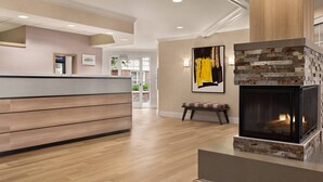 A modern lobby with a wooden reception desk, a stone fireplace, and a bench. - Residence Inn by Marriott Salinas Monterey (Salinas)