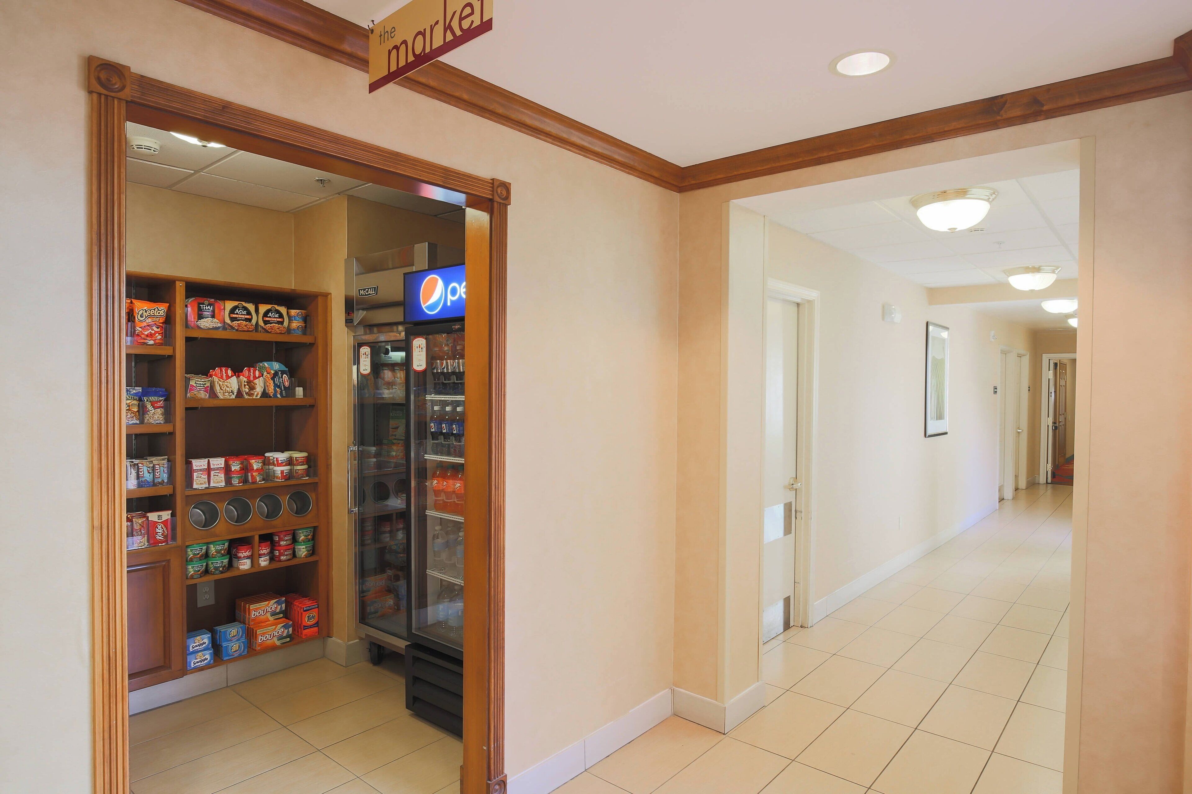 A hallway with a vending machine and shelves stocked with snacks and beverages.