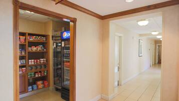 A hallway with a vending machine and shelves stocked with snacks and beverages.