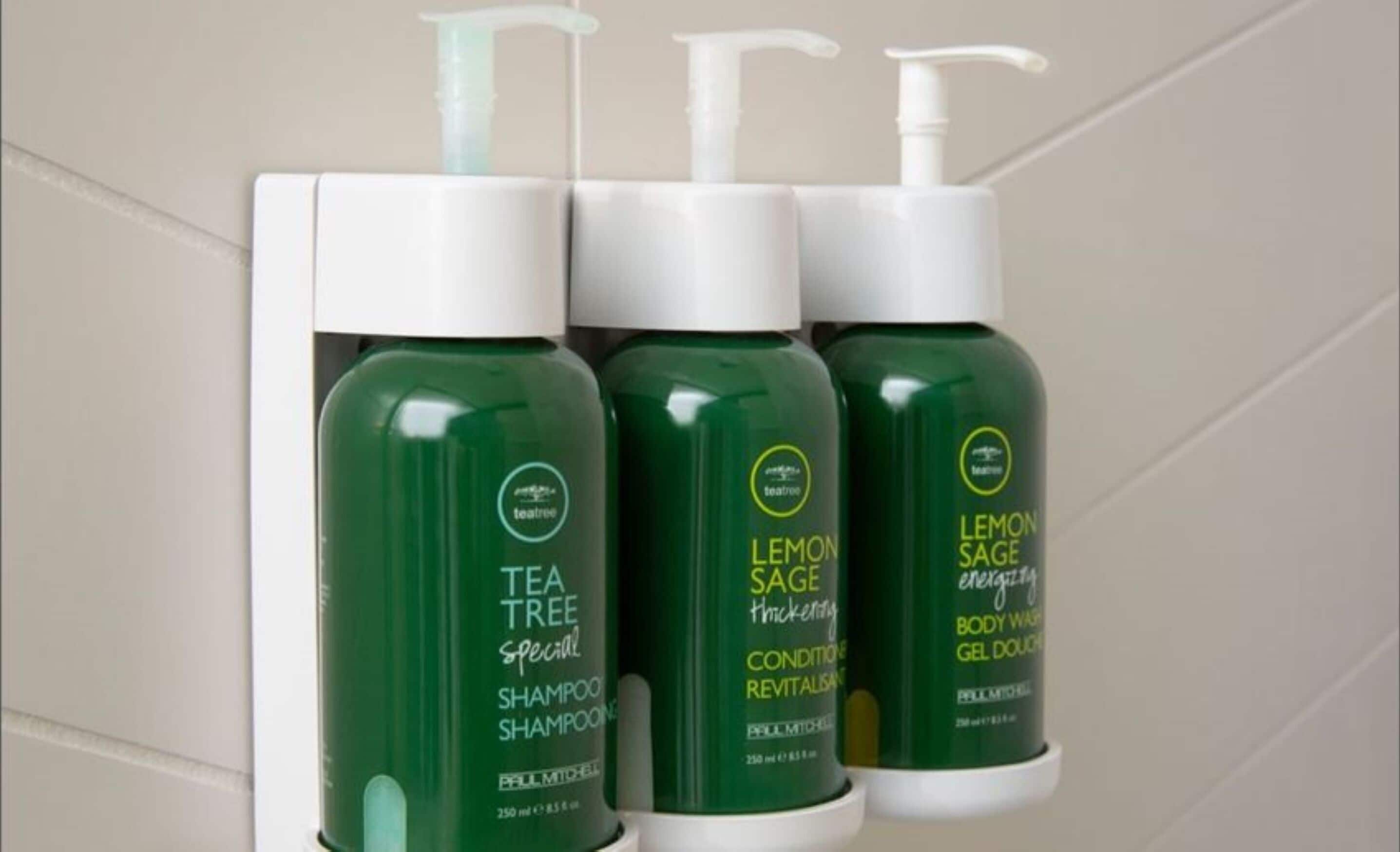 Three bottles of tea tree shampoo and two bottles of lemon sage body wash on a shelf.