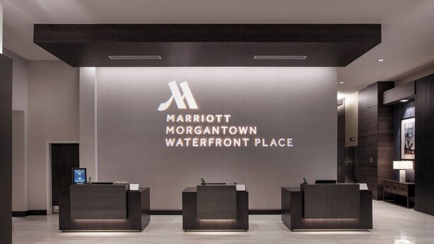 A modern reception area with a large sign for Marriott Morgantown Waterfront Place, featuring three reception desks and a minimalist design. - Morgantown Marriott at Waterfront Place (Morgantown)