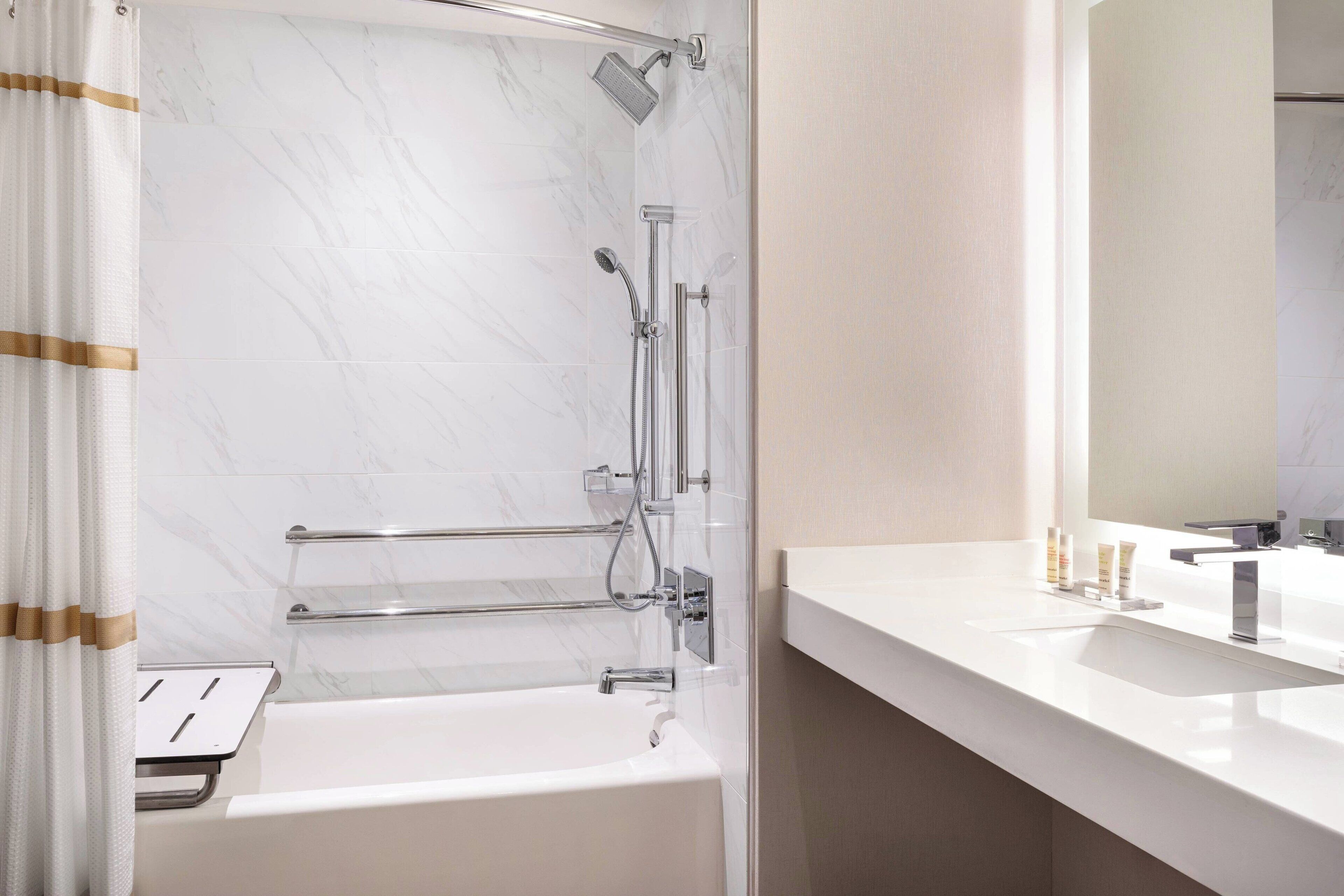 A modern bathroom with a bathtub, shower, and vanity.