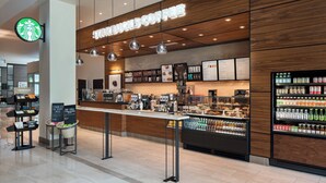 A Starbucks coffee shop with a wooden interior, a counter with a menu, and a refrigerated display of beverages. - Morgantown Marriott at Waterfront Place (Morgantown)