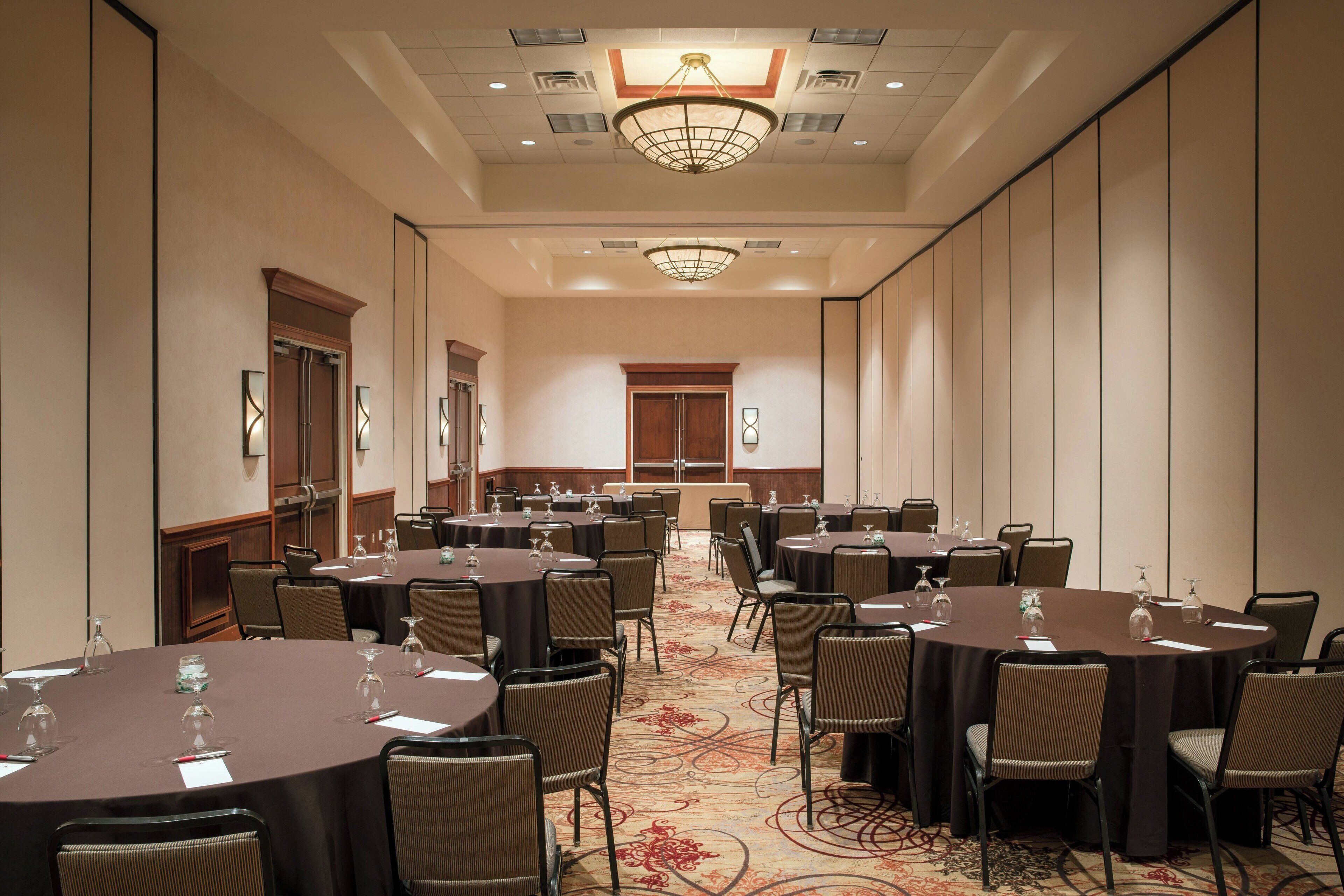 A conference room with round tables, chairs, and a carpeted floor.