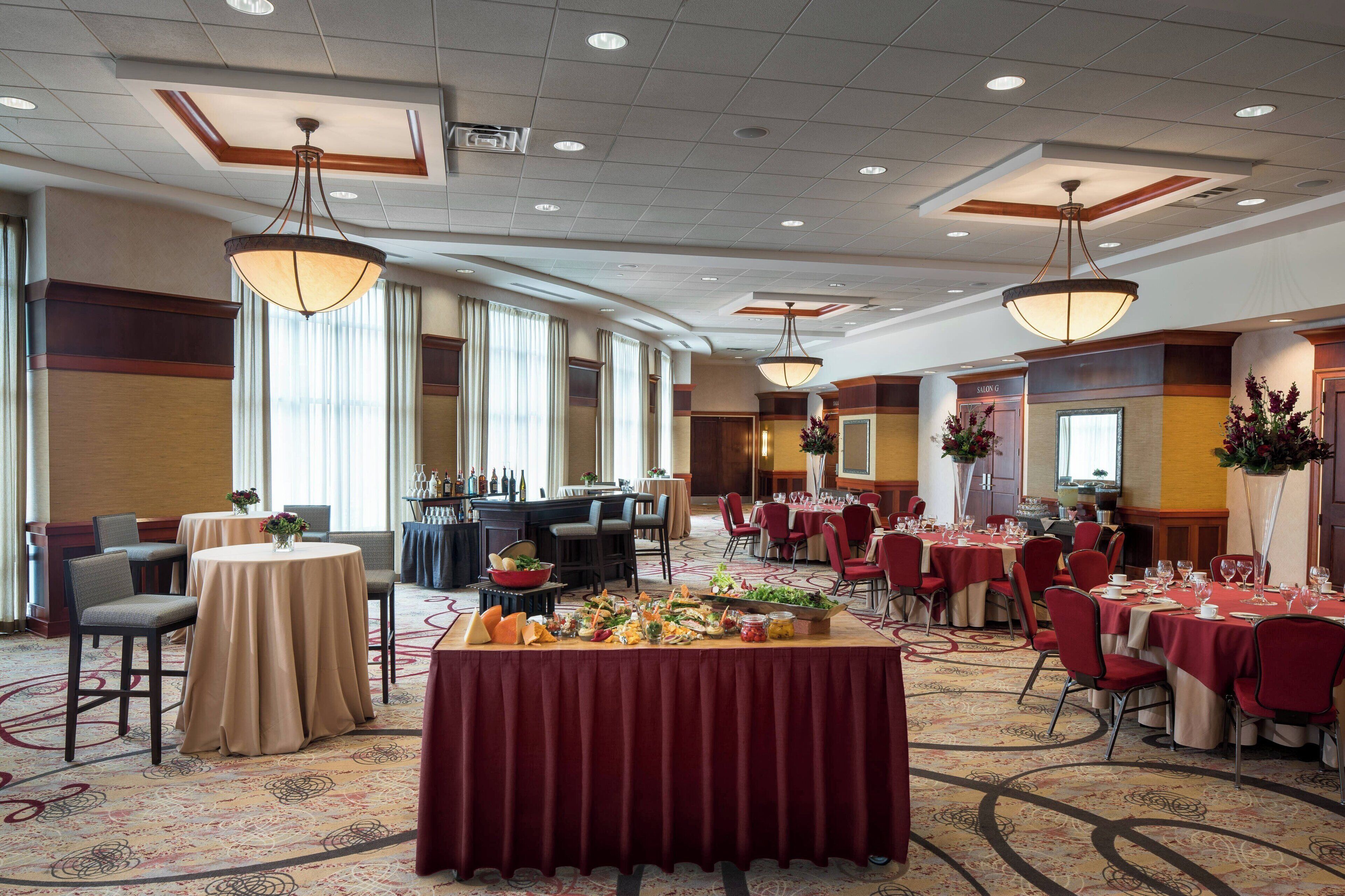 A hotel dining area with round tables, red chairs, and a buffet table.