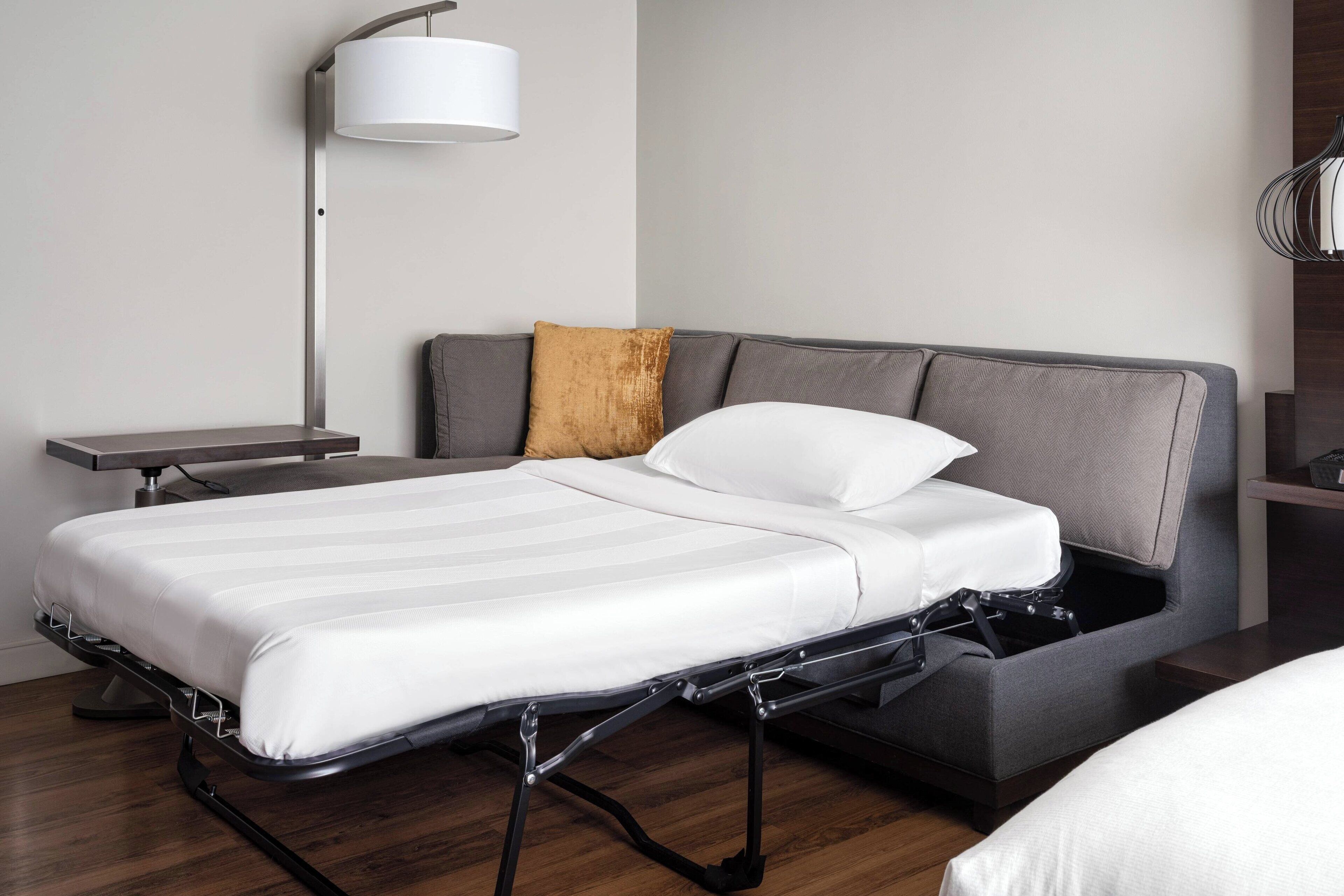 A modern bed with a metal frame, a bedside table, a lamp, and a cushioned headboard.