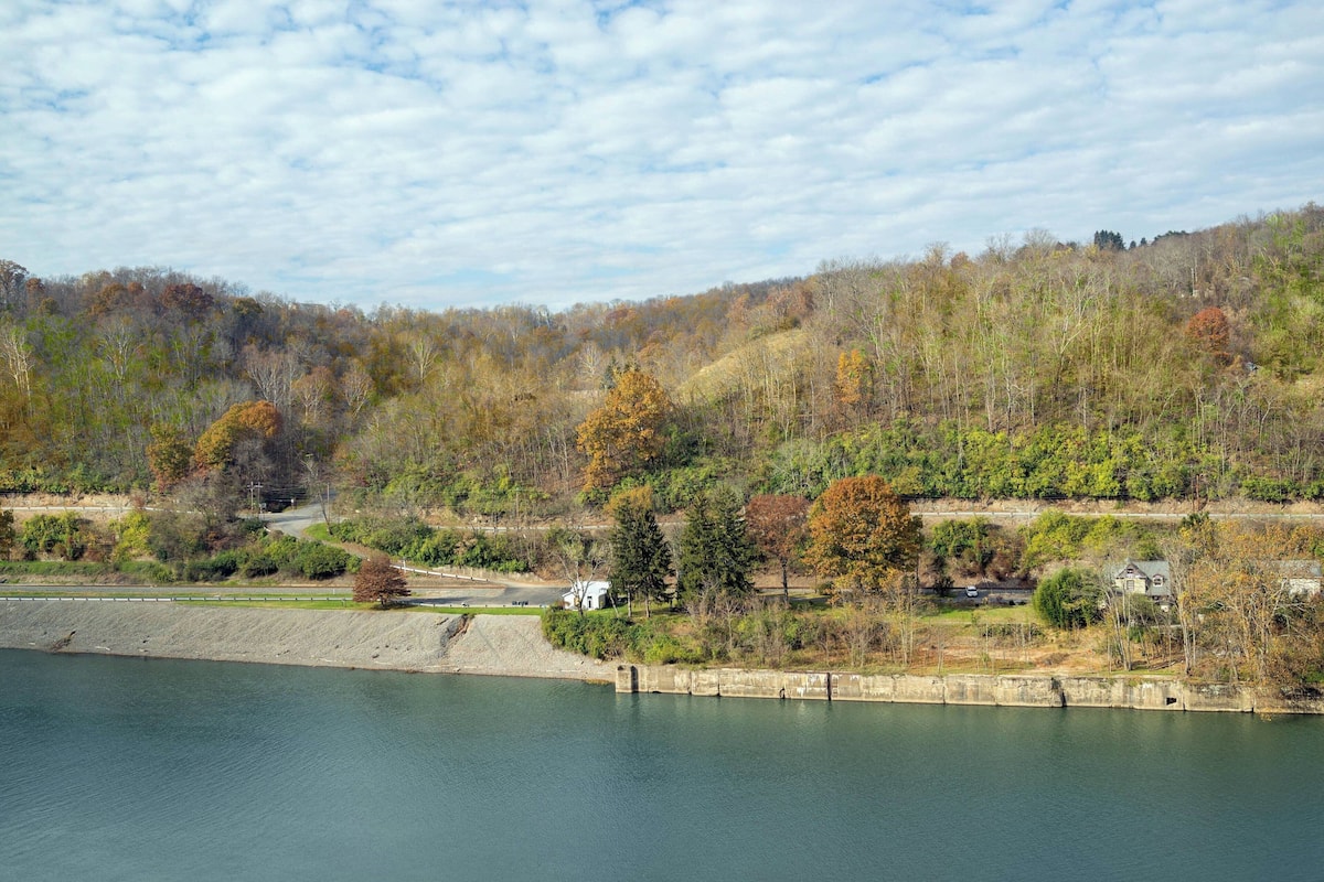 Ein ruhiger See mit einem Stausee, Bäumen und einer Straße.