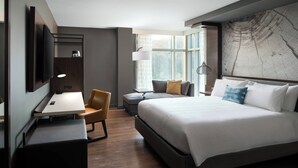 A modern hotel room with a large bed, a desk, and a chair. There is a window with curtains and a map on the wall. - Morgantown Marriott at Waterfront Place (Morgantown)