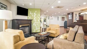 A hotel lobby with a fireplace, sofas, a coffee table, and a reception desk. - Sleep Inn & Suites Jacksonville near Camp Lejeune (Jacksonville)