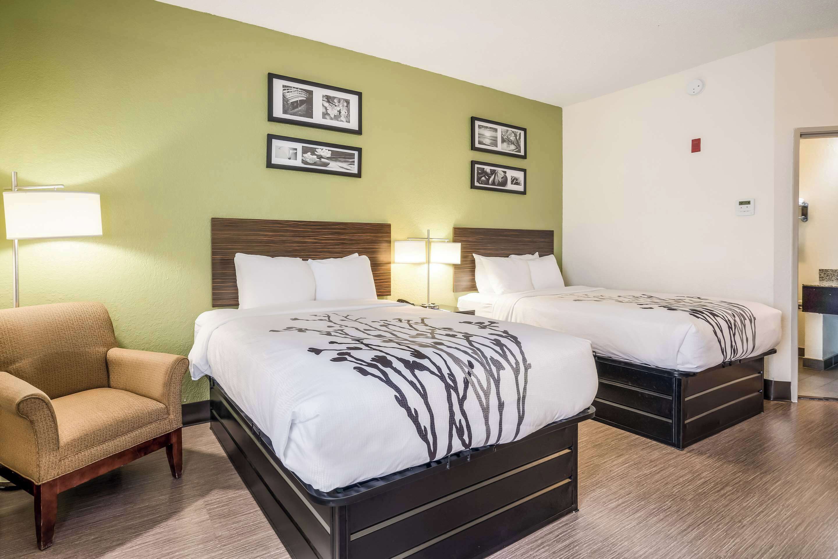 Habitación de hotel con dos camas, una silla y lámparas fijadas a la pared.