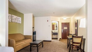 A hotel room with a sofa, a small table, a chair, and a carpeted floor. - Sleep Inn & Suites Jacksonville near Camp Lejeune (Jacksonville)