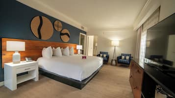 Una habitación de hotel con una cama grande, mesitas de noche, un televisor y una zona de estar con sillones.