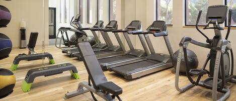 Un gimnasio con cintas de correr, elípticas y diversos equipos de ejercicio.