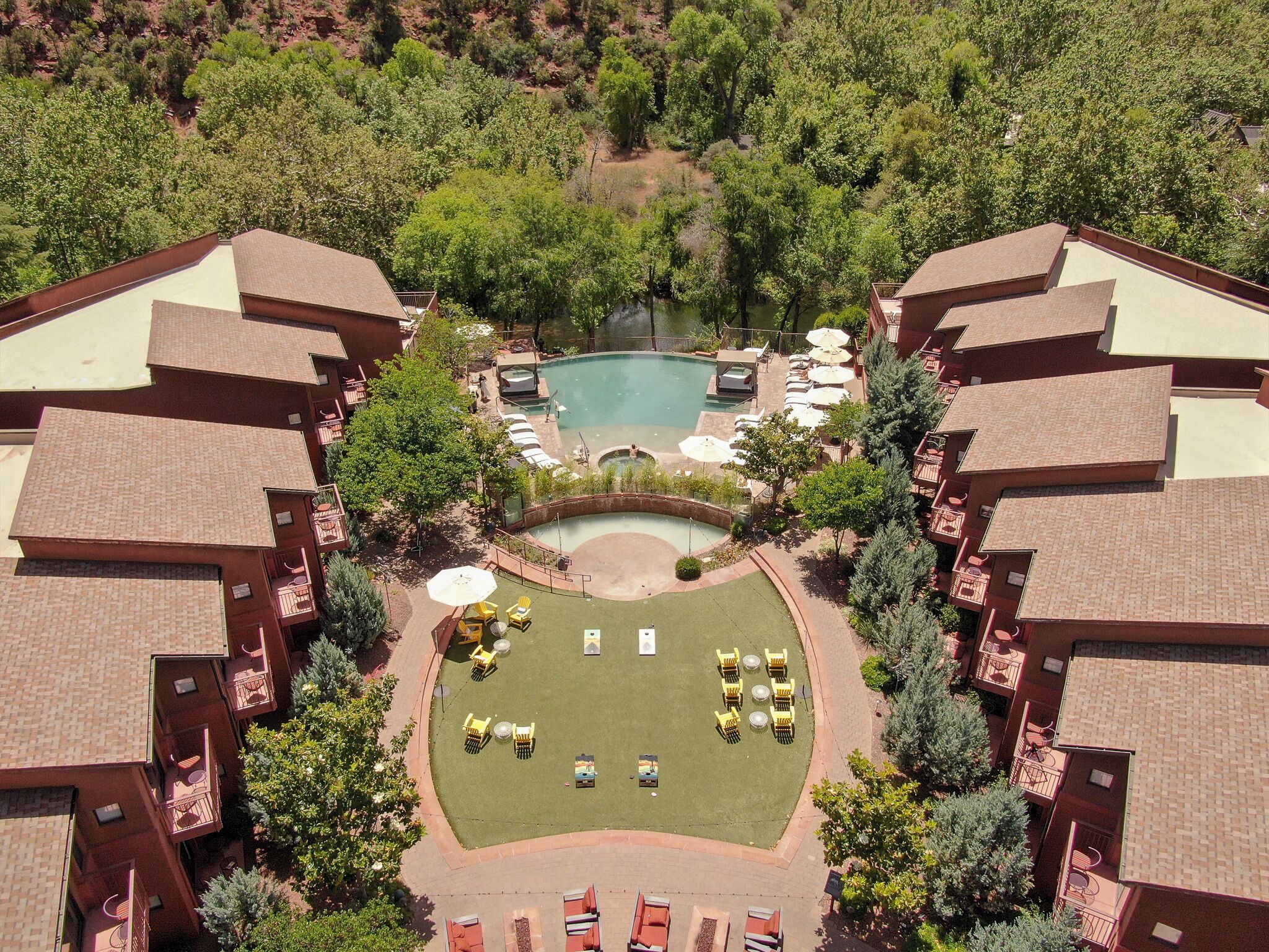 A hotel with a swimming pool, outdoor seating, and a well-maintained lawn.