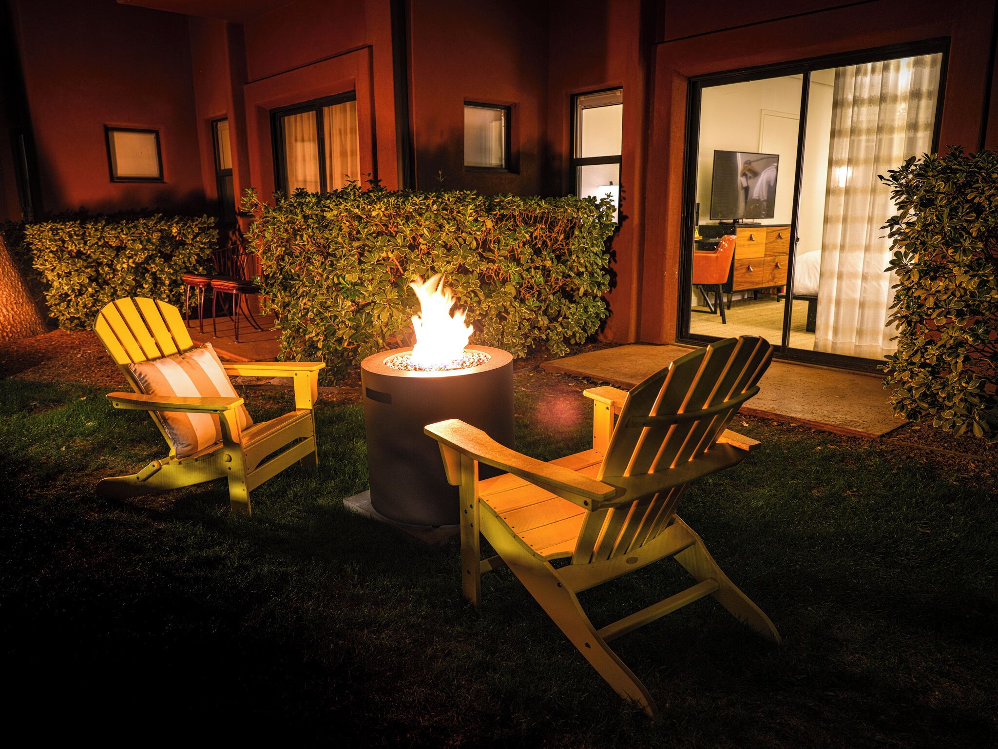 An outdoor seating area with Adirondack chairs and a central fire feature.