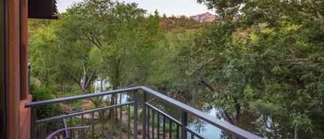 A balcony with a view of a river and trees, and two purple chairs.