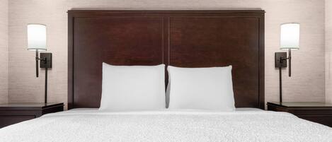 A hotel room with a large bed, two bedside lamps, and a wooden headboard.