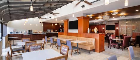 A spacious restaurant with high ceilings, exposed beams, and a mix of seating including booths and tables.