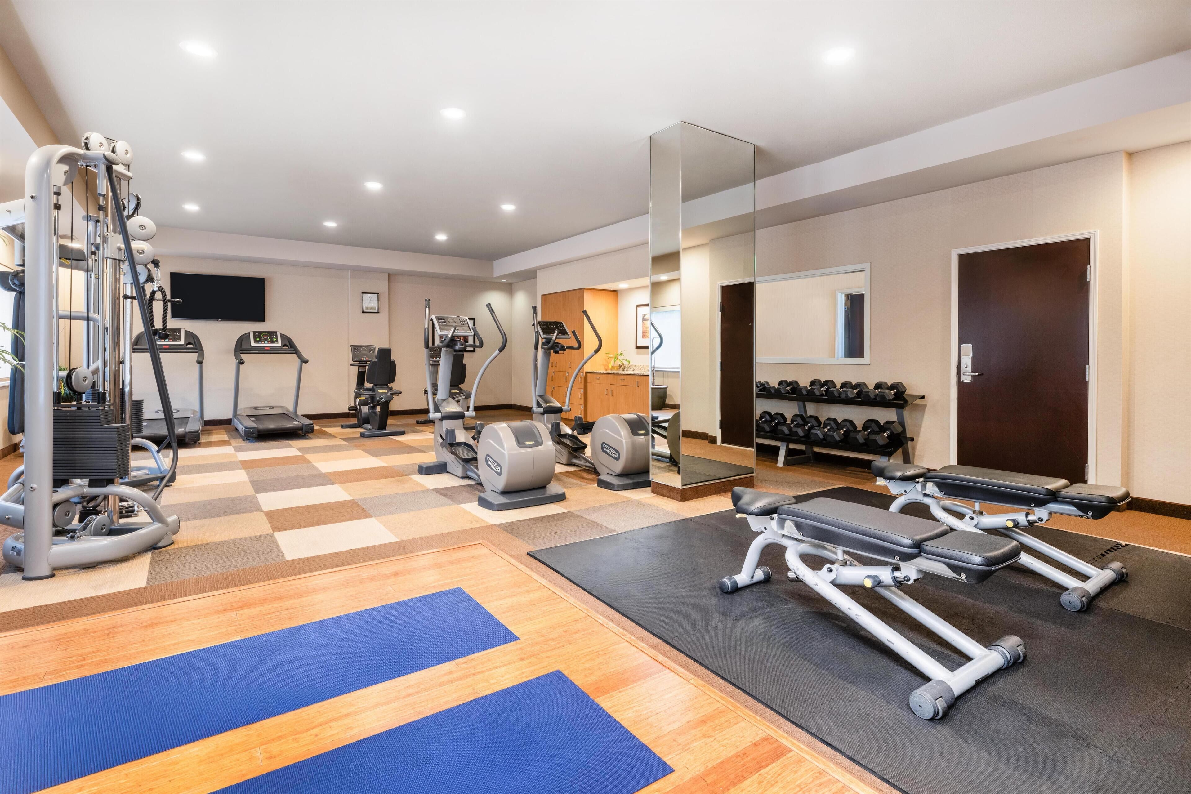 Un gimnasio con cintas de correr, elípticas y pesas sueltas.
