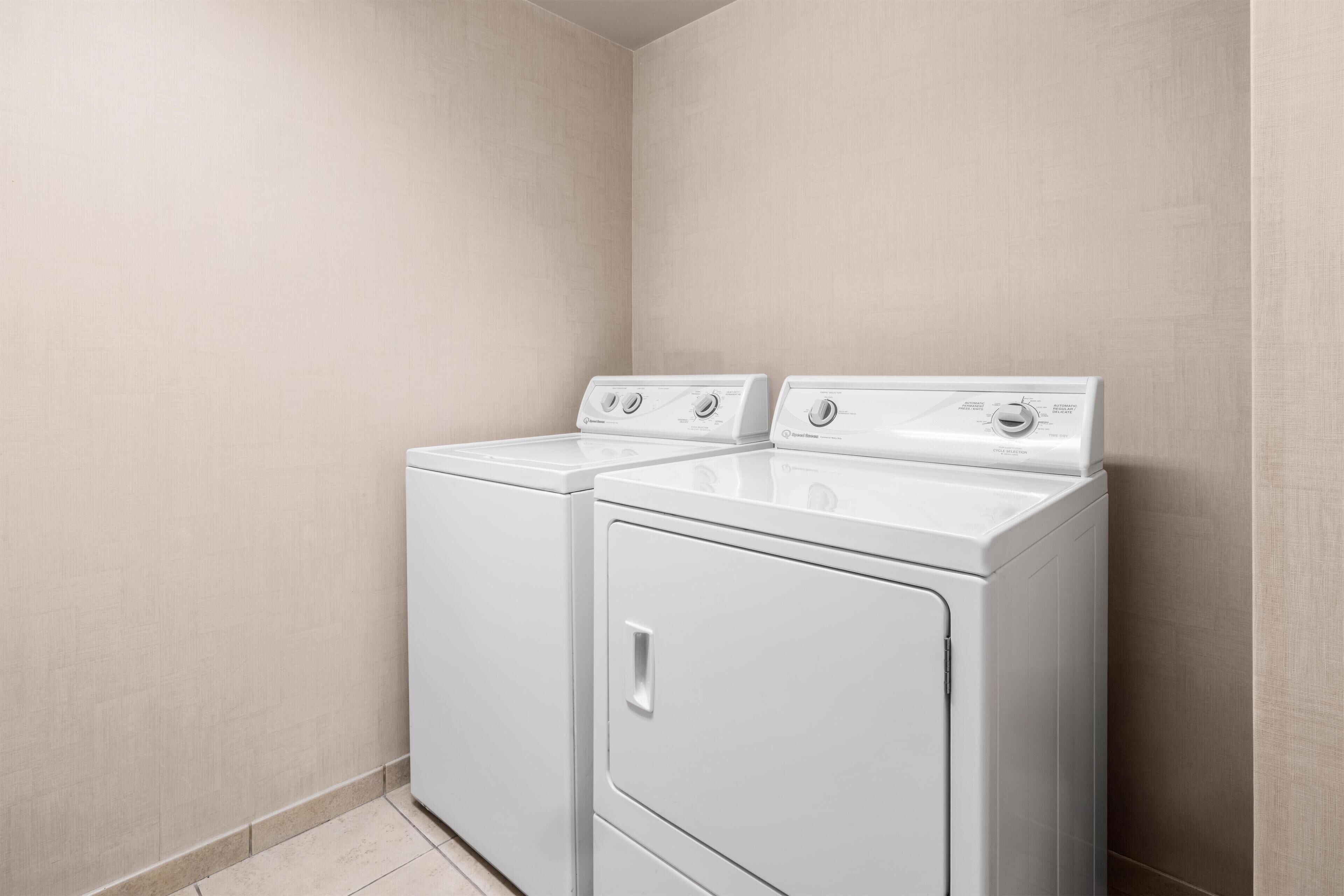 A laundry room with two front-loading washing machines and a dryer.