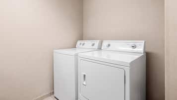 A laundry room with two front-loading washing machines and a dryer.