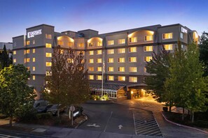 A multi-story hotel with a modern design, featuring a prominent entrance with glass doors and a well-lit facade. - Eastgate Hotel, BW Signature Collection (Bellevue)