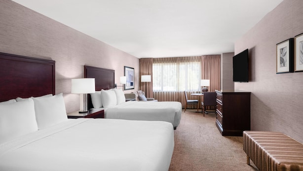 A hotel room with two beds, a desk, a chair, a television, and a window with curtains. - Eastgate Hotel, BW Signature Collection (Bellevue)