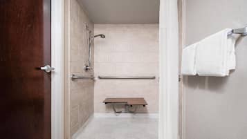 A shower stall with a bench, grab bars, and a towel rack.