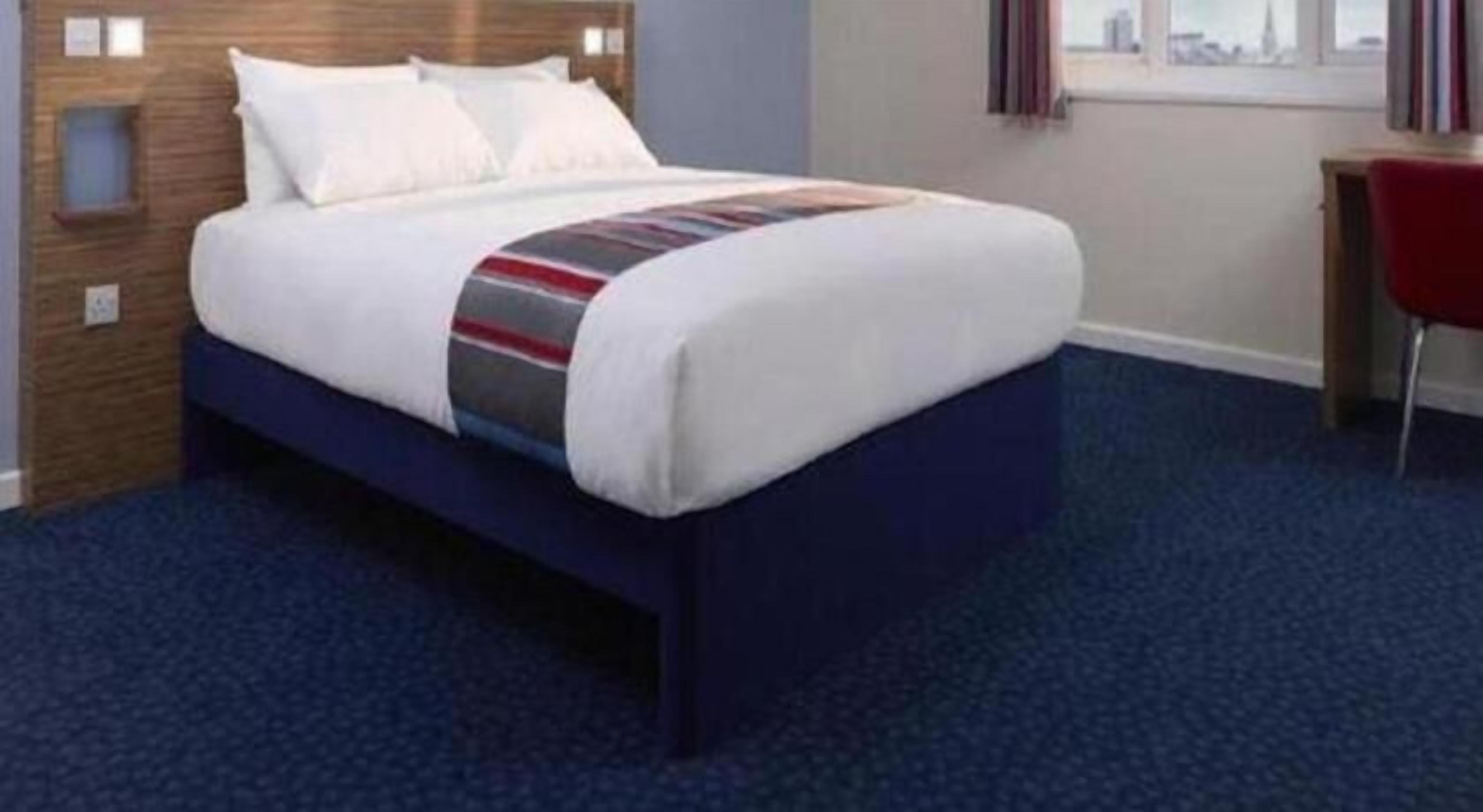 A hotel room with a bed, a desk, and a window.