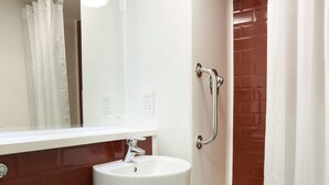 Une salle de bain avec un lavabo blanc, des toilettes et une douche dotée d’une porte en verre.