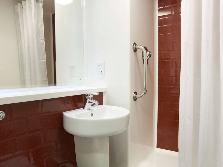 Un baño con un lavamanos blanco, un inodoro y una ducha con puerta de vidrio.