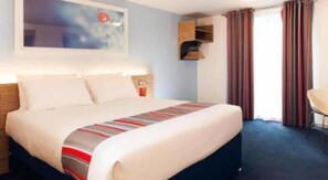A hotel room with a bed, a chair, a desk, and a window with curtains. - Travelodge Dundee Strathmore AVE (Dundee)