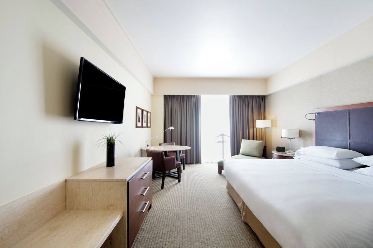 A hotel room with a bed, a desk, a TV, a chair, and a lamp.