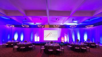 A conference room with round tables, chairs, and a presentation screen.