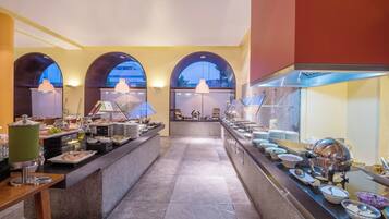 A buffet area with multiple food stations, a marble floor, and arched windows.