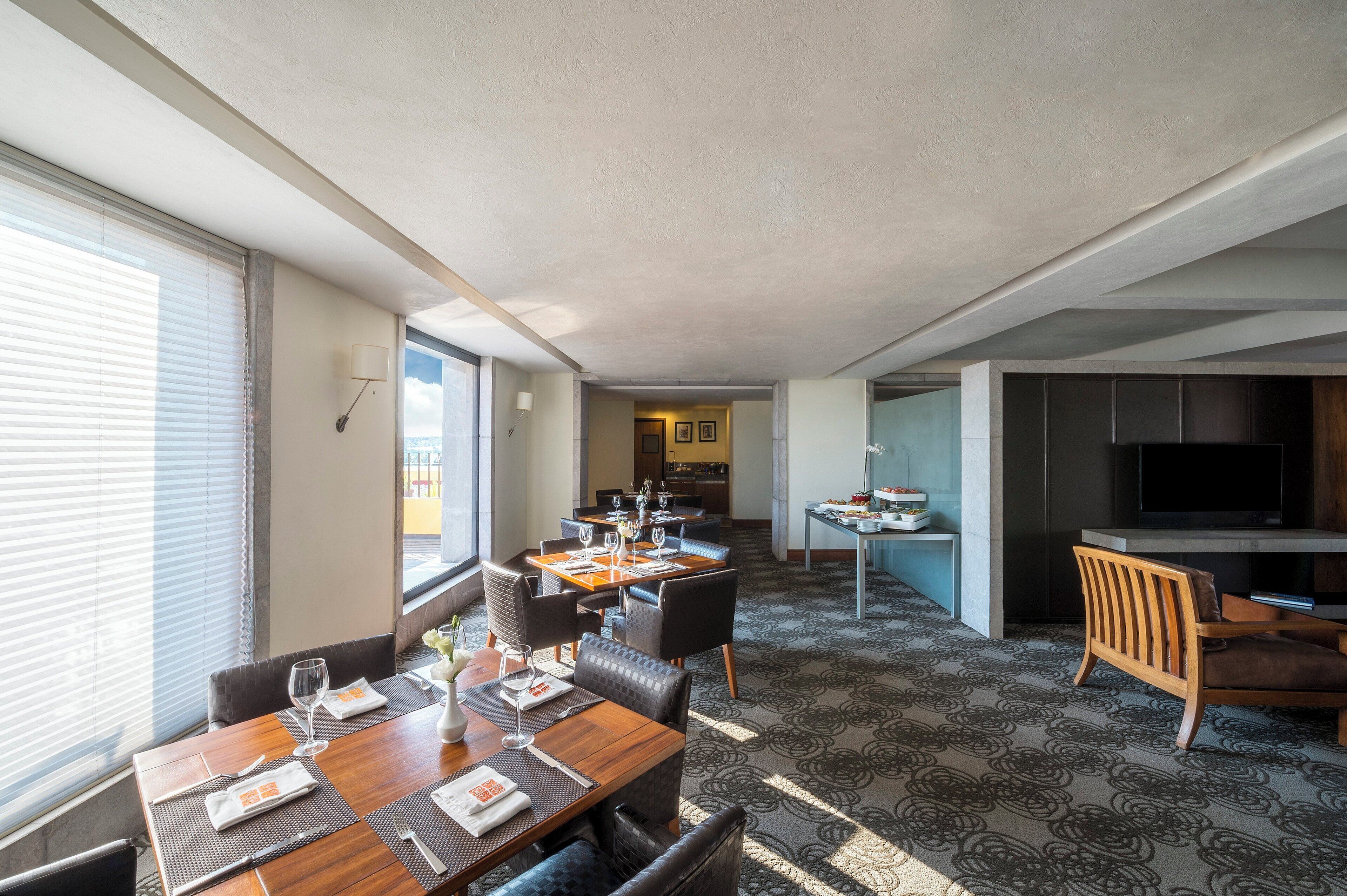 A hotel room with a dining area, a kitchen, and a TV.