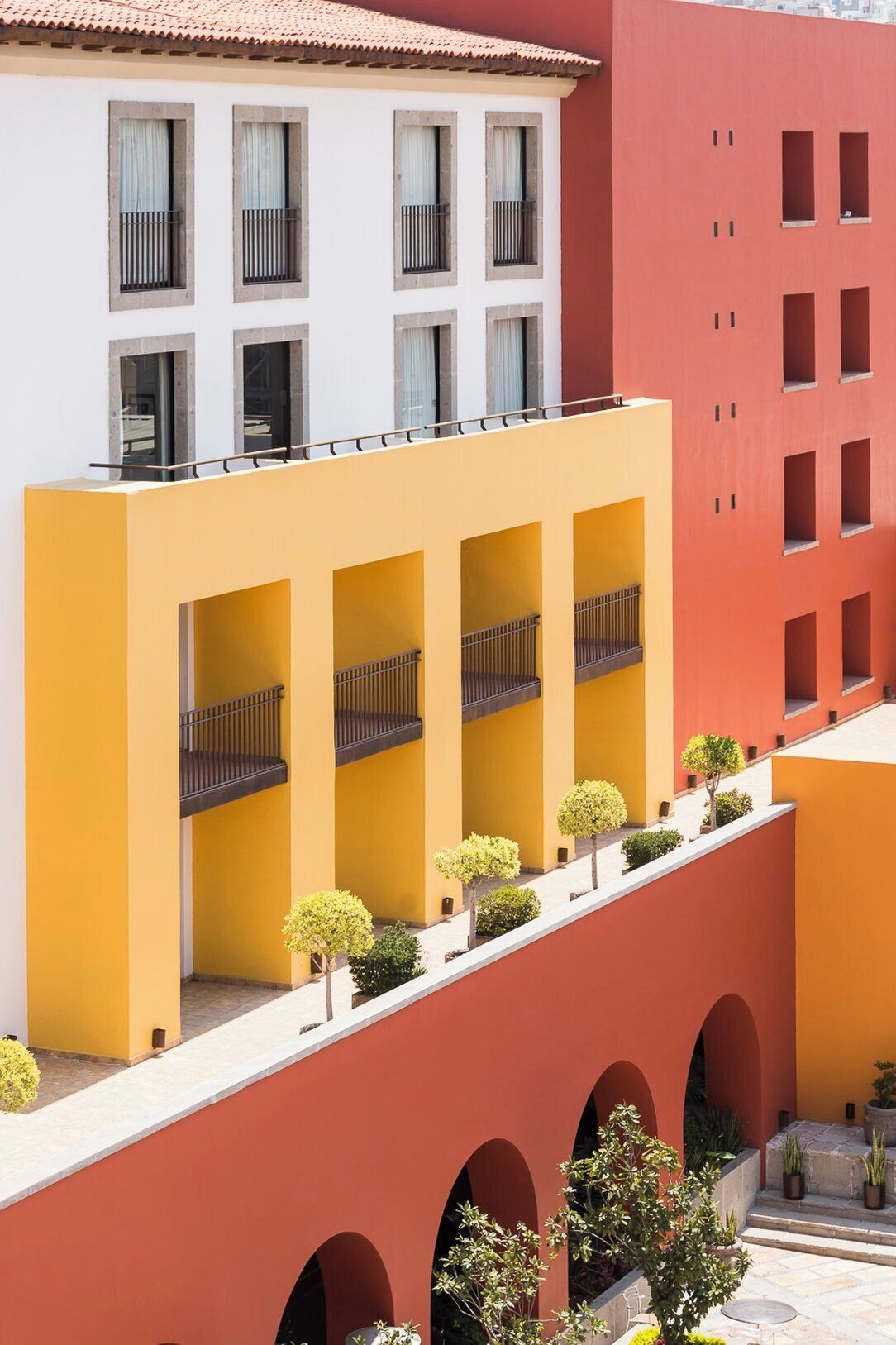 A multi-story building with a yellow and red facade, featuring balconies and arched windows.
