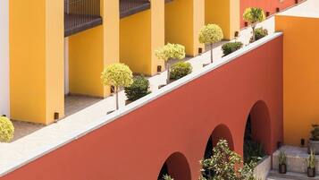 A multi-story building with a yellow and red facade, featuring balconies and arched windows.