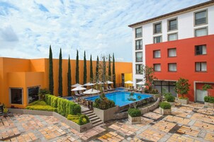 Una piscina al aire libre, sombrillas, sillones reclinables de piscina