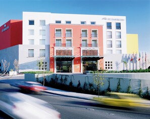 A multi-story hotel with a modern facade, featuring balconies and a prominent entrance.