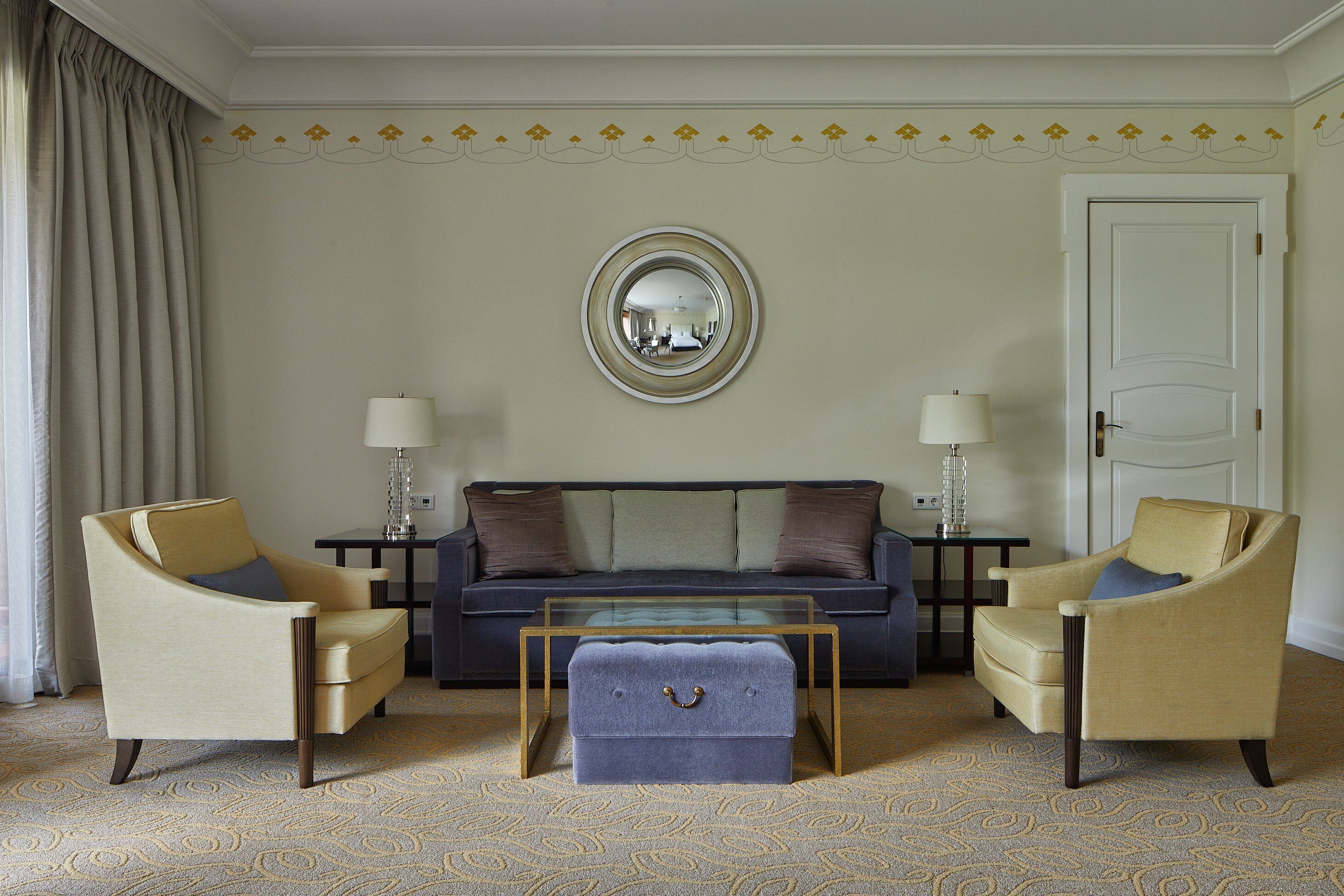 Una sala de estar con un sofá, dos sillones, una mesa de centro y una mesita de noche con lámparas.