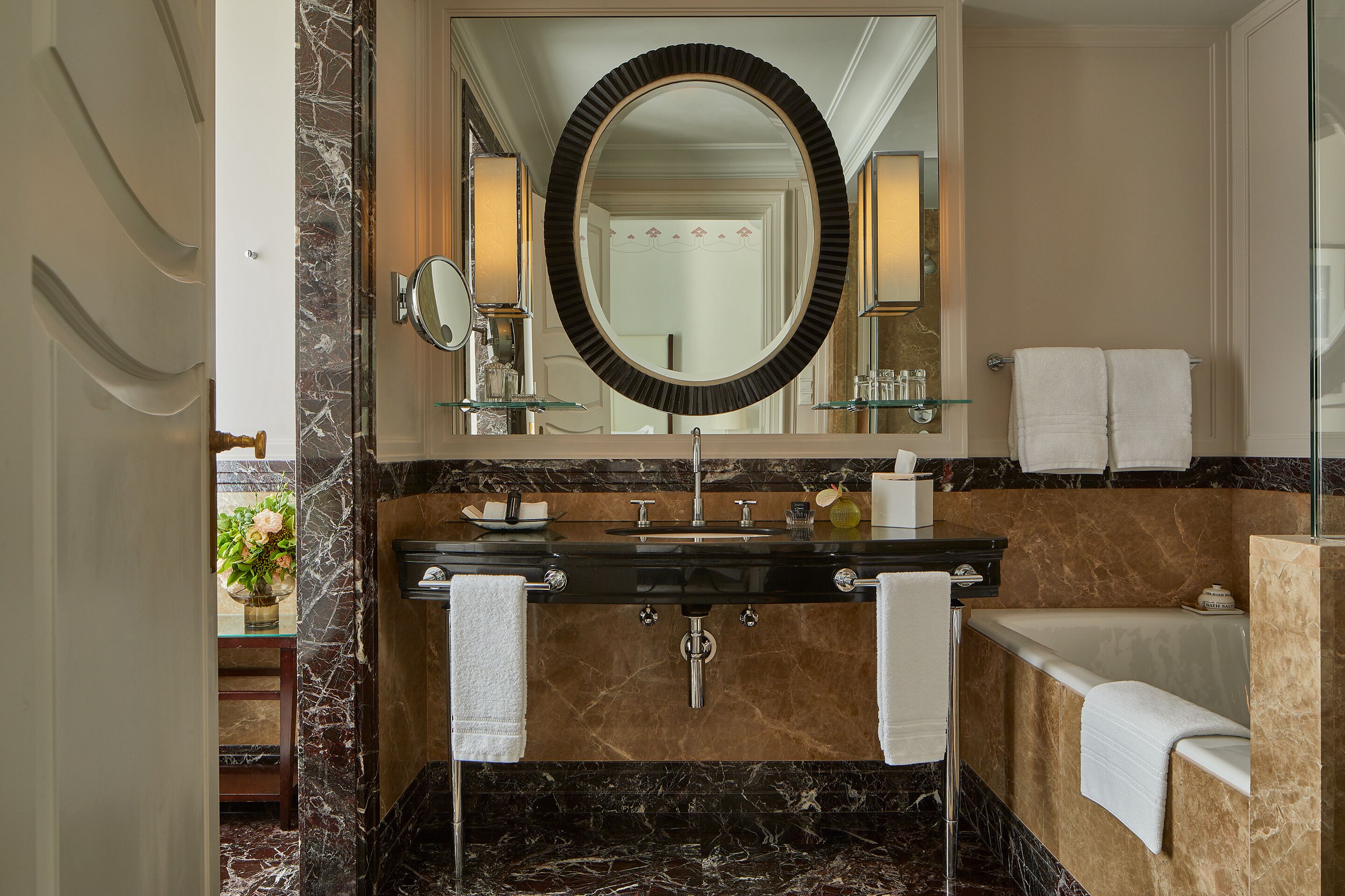Une salle de bain avec un lavabo en marbre, un grand miroir et une baignoire.