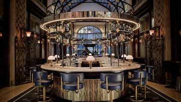 Un espace bar doté d’un bar circulaire, de plusieurs tabourets et d’un comptoir central.
