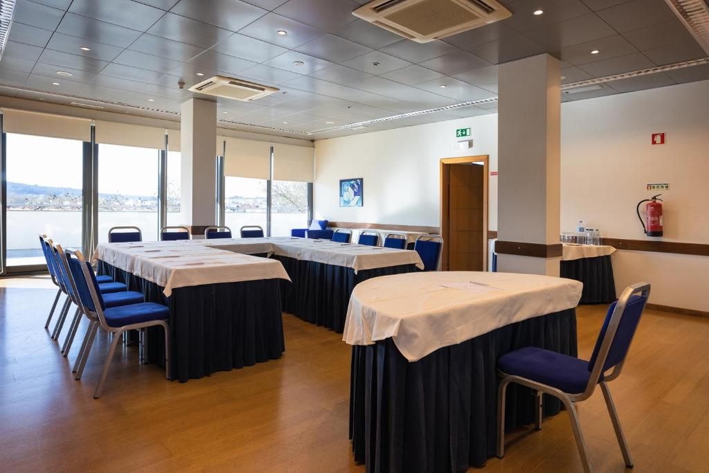 A conference room with tables and chairs, large windows, and a fire extinguisher on the wall.