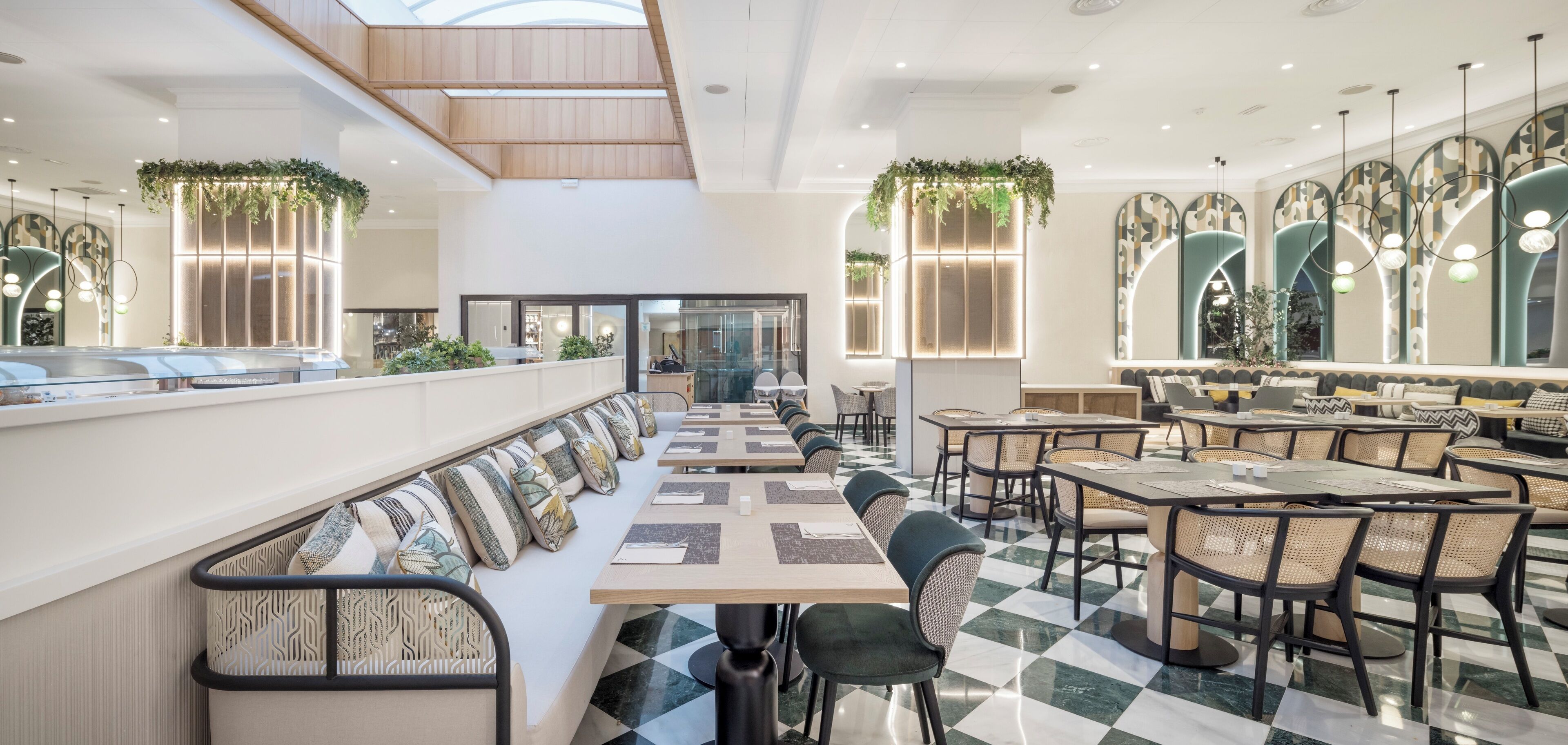 A modern restaurant with a long counter, booths, and high ceilings with skylights.
