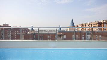 Una piscina al terrat amb vistes a un paisatge urbà, incloent edificis i el campanar d'una església.