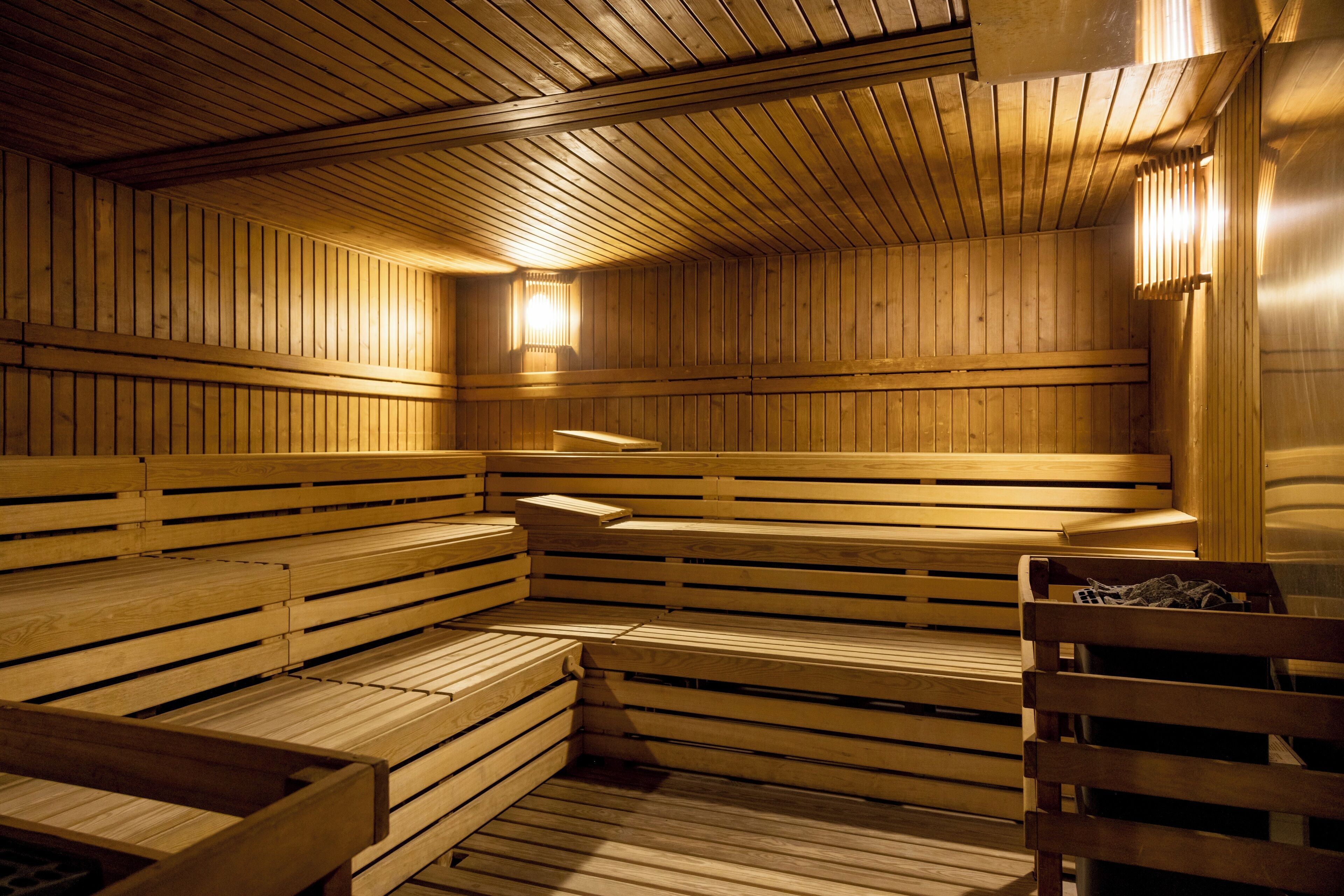 Un sauna avec des bancs en bois, un plafond en bois et un luminaire fixé au mur.